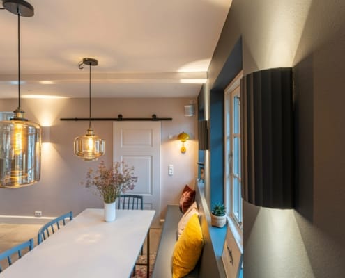 Minimalistiske væglamper i moderne design langs spisebordsvæggen